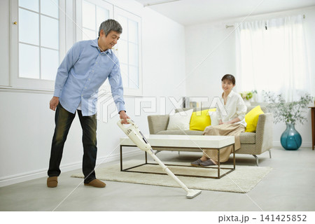 会話をしながら掃除機をかける笑顔の男性と60代の女性 141425852