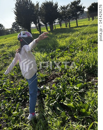 緑の草原で両手を広げてバランスを取りながら歩く女の子・自然の中での外遊び 緑の草原で両手を広げてバランスを取りながら歩く女の子・自然の中での外遊び 141426276