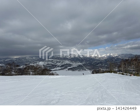 圧雪された白銀のスキー場コースと連なる山々・北海道の冬の大自然 圧雪された白銀のスキー場コースと連なる山々・北海道の冬の大自然 141426449