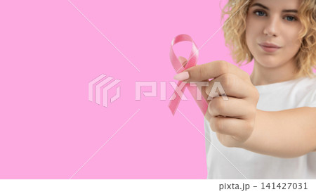 A woman holds a pink ribbon to promote cancer awareness 141427031