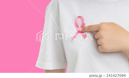 Hand points to pink ribbon on shirt promoting cancer awareness 141427094