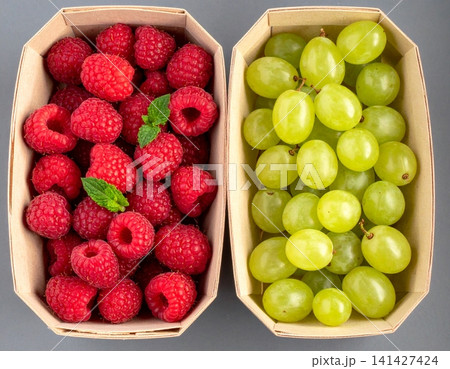 two pulp paper punnets, one filled with fresh red raspbe two pulp paper punnets, one filled with fresh red raspbe 141427424