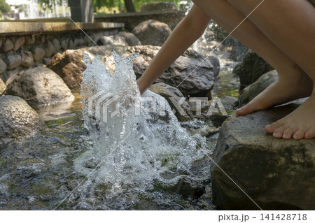 Child's hand splashing water in a rocky stream on a sunny day Child's hand splashing water in a rocky stream on a sunny day 141428718