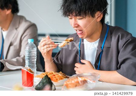 コンビニ弁当を食べて不味そうな表情をする若いアジア人男性 コンビニ弁当を食べて不味そうな表情をする若いアジア人男性 141429979
