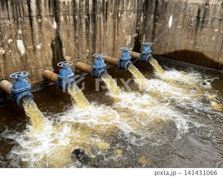 Hydraulic engineering system discharging liquid effluent, showcasing rusted blue gate valves controlling volumetric flow rate, hydrodynamic fluid pressure, and environmental drainage mechanism 141431066