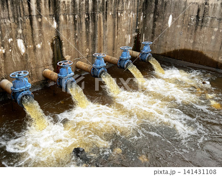 Hydraulic engineering system discharging liquid effluent, showcasing rusted blue gate valves controlling volumetric flow rate, hydrodynamic fluid pressure, and environmental drainage mechanism 141431108