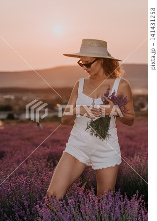 Lavender woman sunset, a young lady wearing a summer hat and holding flowers in a purple blooming field at golden hour Lavender woman sunset, a young lady wearing a summer hat and holding flowers in a purple blooming field at golden hour 141431258