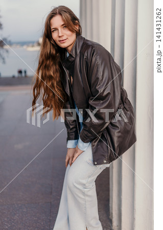 Woman leather jacket urban portrait of a stylish young female model posing against a white textured wall near the waterfront Woman leather jacket urban portrait of a stylish young female model posing against a white textured wall near the waterfront 141431262