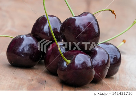 Close-up of a Pile of Dark Red English Morello cherries, Prunus ceruss, on a Rustic Wooden Surface, Fresh and Juicy Harvest 141431716
