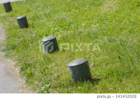 Row of metal parking bollards on a green grass lawn Row of metal parking bollards on a green grass lawn 141432028