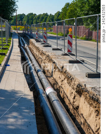 Urban district heating pipeline installation in roadside trench during infrastructure modernization works Urban district heating pipeline installation in roadside trench during infrastructure modernization works 141432503