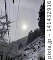 雪の山並みと雲の間から差し込む太陽の光 141432916