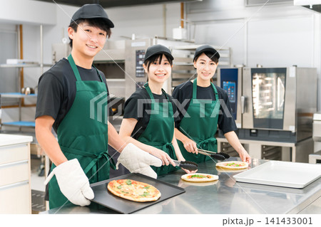 飲食店の厨房,バクヤードで働くユニフォーム姿の調理スタッフの男女 141433001