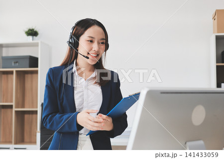 Smiling Asian Woman Telemarketing Agent with Headset Working at Smiling Asian Woman Telemarketing Agent with Headset Working at 141433059