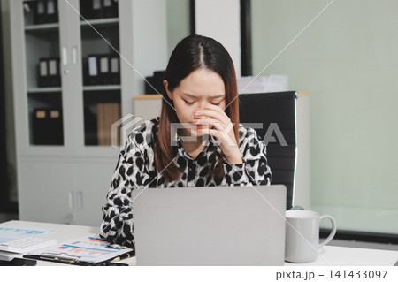 Tried young Asian office employee feeling sick and have a headache from a long working day at office Tried young Asian office employee feeling sick and have a headache from a long working day at office 141433097