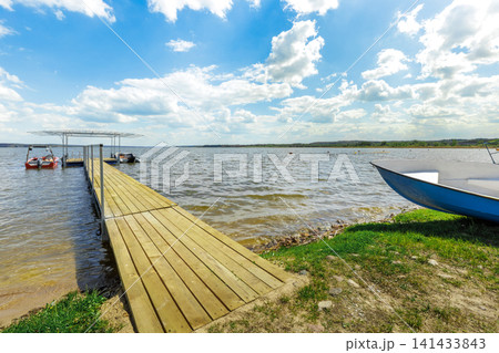 Wooden Pier and Moored Boats on a Scenic Lake Wooden Pier and Moored Boats on a Scenic Lake 141433843
