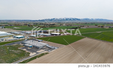 Aerial View Of Farmland And Industrial Buildings Near Mountains 141433976