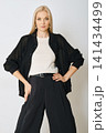 Fashion model poses in black shirt and trousers on white background with natural light 141434499