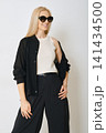 Model posing in indoor studio wearing black outfit and sunglasses 141434500