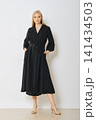 Woman poses in long black dress with pockets in studio 141434503