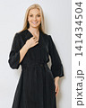 Woman showing black dress with long sleeves in studio setting 141434504