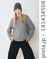 Woman wearing gray sweater and hat posing indoors 141434508
