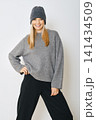 Woman wearing grey sweater and hat posing in studio with simple background 141434509