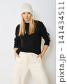 Woman wearing black sweater and white pants posing indoors 141434511