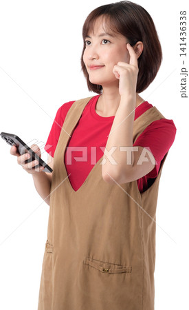 Asian woman holding smartphone with thoughtful expression isolated on transparent background posing wearing casual outfit while gesturing with finger for creative concept. PNG file format 141436338