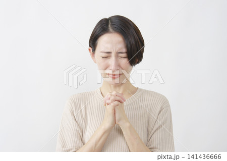 白背景で切実に願う40代女性 141436666