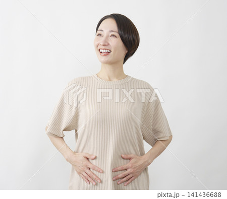 白背景でお腹を押さえて安堵する40代女性 141436688
