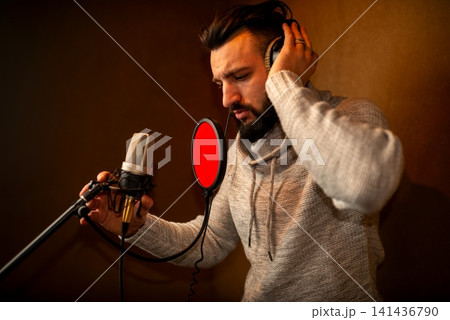 Bearded man singing into studio microphone with pop filter Bearded man singing into studio microphone with pop filter 141436790