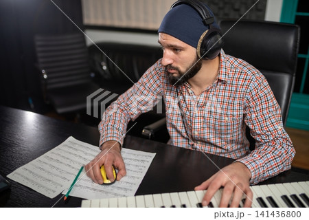 Sound engineer editing music at a studio workstation Sound engineer editing music at a studio workstation 141436800
