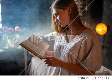 Young female patient reading a book alone in her hospital bed 141436814