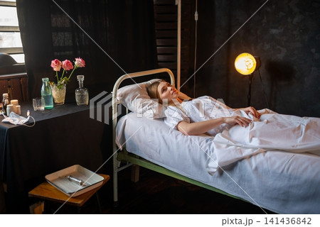Young sick woman lying alone in an old hospital bed Young sick woman lying alone in an old hospital bed 141436842