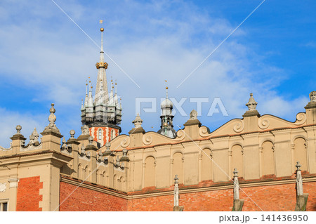 A detailed view of a historic European castle facade featuring intricate spires, high stone walls, and decorative architectural elements against a cloudy sky A detailed view of a historic European castle facade featuring intricate spires, high stone walls, and decorative architectural elements against a cloudy sky 141436950