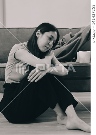 Young Asian woman sitting in bed and holding her head in pain with headache, feeling depressed and suffering Young Asian woman sitting in bed and holding her head in pain with headache, feeling depressed and suffering 141437255