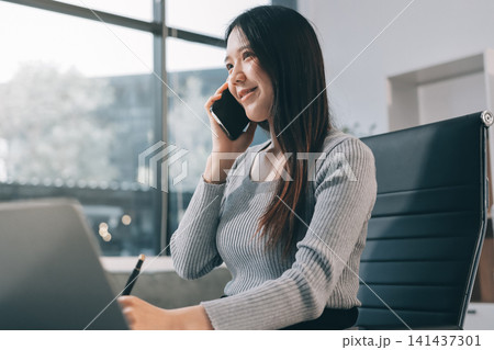young woman is working on laptop in modern office environment, showcasing focused and productive atmosphere. She is dressed in professional white shirt, with coffee cup and small plant on table, young woman is working on laptop in modern office environment, showcasing focused and productive atmosphere. She is dressed in professional white shirt, with coffee cup and small plant on table, 141437301