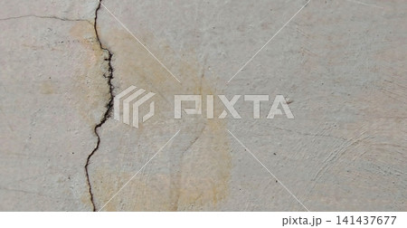 A weathered concrete wall with deep vertical cracks. 141437677