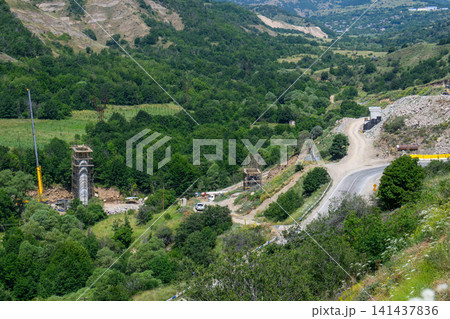 Valley construction project with crane, trucks 141437836