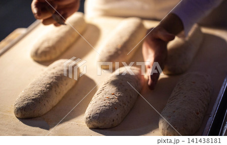 Hands shaping dough loaves on factory conveyor belt before baking process artisan bread production at bakery plant Hands shaping dough loaves on factory conveyor belt before baking process artisan bread production at bakery plant 141438181