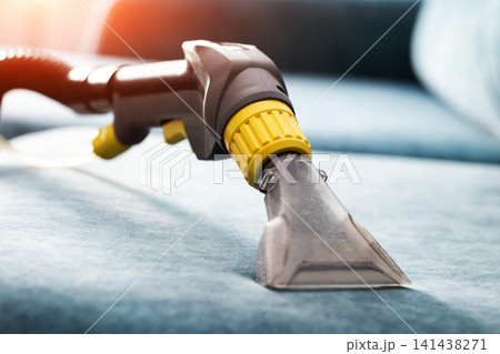 Upholstery cleaning nozzle of powerful wet vacuum cleaner removing dirt and stains from fabric sofa couch interior close up shot of housework process Upholstery cleaning nozzle of powerful wet vacuum cleaner removing dirt and stains from fabric sofa couch interior close up shot of housework process 141438271