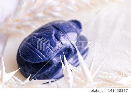 Lapis lazuli scarab beetle amulet among dried oat spikelets on linen. Lapis lazuli scarab beetle amulet among dried oat spikelets on linen. 141438357