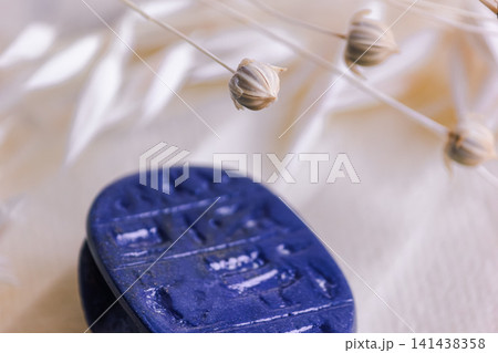 Macro shot of dried flax seed pods above blue stone amulet. 141438358