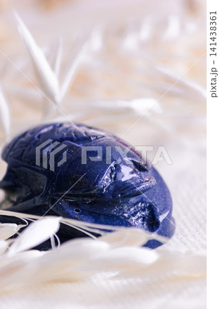Macro shot of lapis lazuli scarab amulet on light linen fabric. Macro shot of lapis lazuli scarab amulet on light linen fabric. 141438361