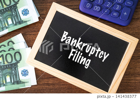 Bankruptcy Filing text on black chalkboard with euro banknotes and calculator on wooden desk, financial law concept 141438377