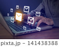 Person typing on laptop with glowing email envelope icons flying, digital communication and email marketing concept 141438388