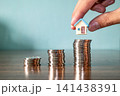 Hand placing toy house on top of stacked coins, real estate investment and savings concept 141438391