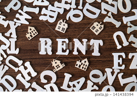 RENT word spelled with letter tiles and toy houses on scattered letters wooden background, real estate concept RENT word spelled with letter tiles and toy houses on scattered letters wooden background, real estate concept 141438394