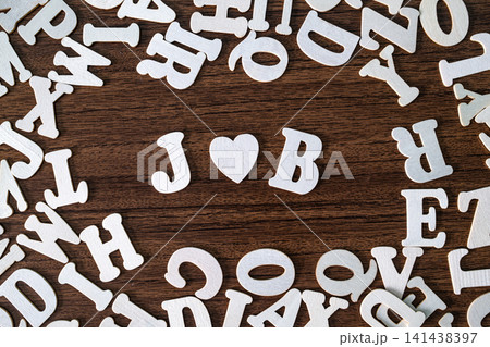 JOB word with heart symbol spelled with letter tiles on scattered letters wooden background, employment and career concept 141438397